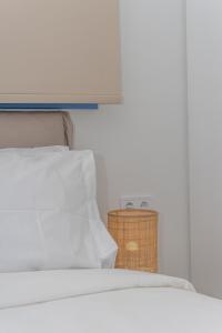 a white bed with a white pillow and a basket at Greek Beach House Complex B4 in Nydri