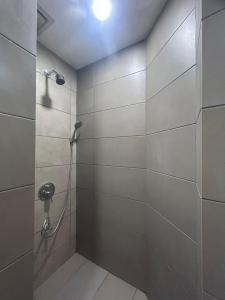 uma casa de banho com um chuveiro e uma parede de azulejos em The Elopura Hotel em Sandakan