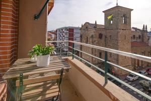 einen Balkon mit einem Holztisch und einer Kirche in der Unterkunft VIVIENDAS CURTO - Piso en el corazón de Castro junto al puerto in Castro-Urdiales