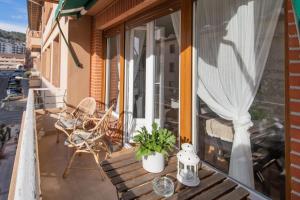 einen Balkon mit einer Holzbank und einem Fenster in der Unterkunft VIVIENDAS CURTO - Piso en el corazón de Castro junto al puerto in Castro-Urdiales