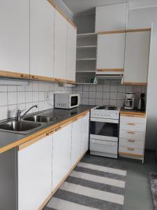a kitchen with white cabinets and a sink at Lepaan Kartanon Toimela in Lepaa