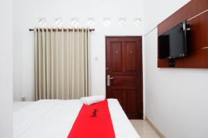 a bedroom with a bed and a flat screen tv at RedDoorz Syariah near Exit Tol Krapyak Semarang in Kalibanteng-kidul