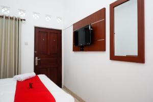 1 dormitorio con 1 cama y TV en la pared en RedDoorz Syariah near Exit Tol Krapyak Semarang en Kalibanteng-kidul