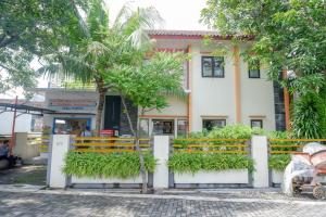 a building with a fence and trees in front of it at RedDoorz Syariah near Exit Tol Krapyak Semarang in Kalibanteng-kidul