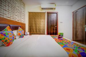 1 dormitorio con 1 cama grande y almohadas coloridas en FabHotel Sain Dass, en Kānpur