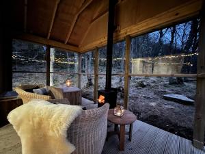 un porche cubierto con chimenea, sillas y mesa en The Dell at Glenlivet en Glenlivet