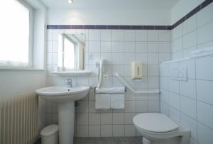 La salle de bains blanche est pourvue d'un lavabo et de toilettes. dans l'établissement Hôtel Restaurant Au Lion d'Or, à Burnhaupt-le-Haut
