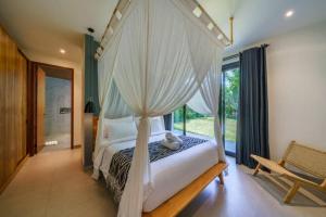 ein Schlafzimmer mit einem Himmelbett und einem Fenster in der Unterkunft Villa Satiya - Unique and stylish 4-bdr pool villa in Pererenan! in Canggu