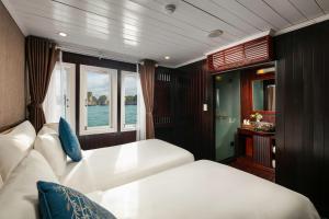 a bedroom with two beds and a window on a boat at La Regina Classic Cruise in Ha Long