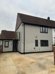 a white house with a driveway in front of it at The grey retreat in Shepperton