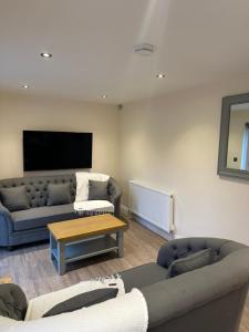 ein Wohnzimmer mit 2 Sofas und einem TV in der Unterkunft The grey retreat in Shepperton