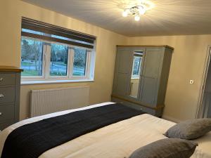sypialnia z łóżkiem z komodą i oknem w obiekcie The grey retreat w mieście Shepperton