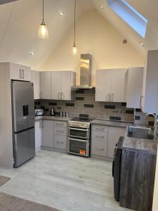 una cucina con armadietti bianchi ed elettrodomestici in acciaio inossidabile di The grey retreat a Shepperton