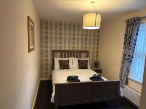 Wanlockhead的住宿－3 Dialknowe Holiday Cottage - Wanlockhead，一间卧室,配有一张带两顶帽子的床