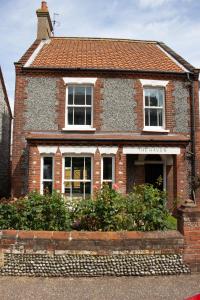 a brick house with two windows on a street at The Haven in Sheringham