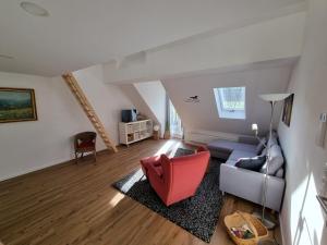 ein Wohnzimmer mit einem Sofa und einem roten Stuhl in der Unterkunft Grundmühle - Kleines Ferienappartement auf dem Ponyhof 