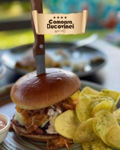 Un sándwich y patatas fritas en un plato con un cuchillo. en Complex Turistic Comoara Bucovinei, en Corlata