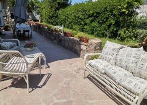 un patio con 2 sillas blancas y una mesa en Casa scopelliti, en Calasetta
