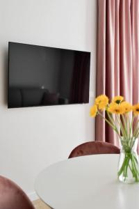 a vase of yellow flowers on a table with a tv at Parko Aveniu Apartamentai B4 in Birštonas