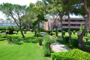 un parc avec des arbres et de la pelouse et un bâtiment dans l'établissement Premium Apartment Mono C4, à Marina di Bibbona