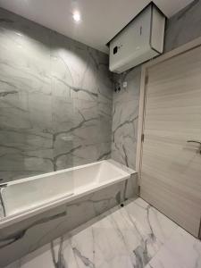 a bathroom with a white tub and a marble wall at Skylark 2 Apartment with Terrace in Is-Swieqi