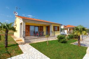 a small yellow house with palm trees in a yard at Villa Bali in Kaštelir