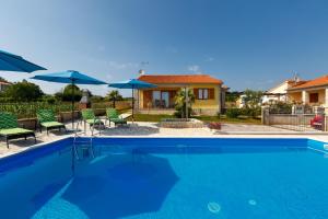 a swimming pool with chairs and umbrellas and a house at Villa Bali in Kaštelir