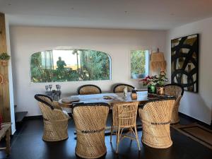 a dining room with a table and wicker chairs at Maison "LA ROSALINDA-2B" Ghisonaccia in Ghisonaccia