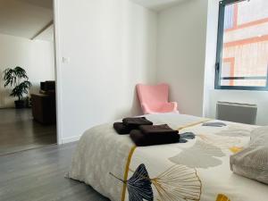 um quarto com uma cama e uma cadeira rosa em LE CAPUCIN em Rodez