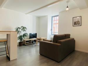 uma sala de estar com um sofá e uma televisão em LE CAPUCIN em Rodez
