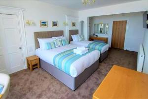 a hotel room with two beds and a table at Richmond Hotel in Aberystwyth