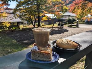 una taza de café y dos platos de comida en una mesa en Tanigawa Valley Lodge & Coffee Roastery en Minakami