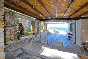 une terrasse avec un mur en pierre, une table et des chaises dans l'établissement Villa Eliza with a swimming pool and sea view in the area of Otzia, on the island of Kea, à Otziás