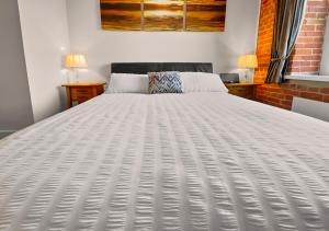 a large white bed in a room with two lamps at The Granary in Gosport