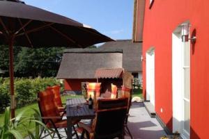 a patio with a table and chairs and an umbrella at Ferienhaus Strandhafer in Stubbenfelde +16 photos