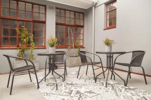 a patio with two tables and chairs and windows at The City Club in Cape Town