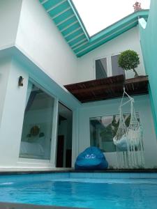 a house with a swimming pool and a hammock next to a window at Villa Giyor in Nusa Lembongan