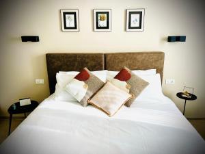 uma cama branca com almofadas num quarto em Lucentum em Prato
