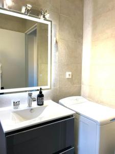 y baño con lavabo, espejo y aseo. en Magnifique T3 - Saint-Clair - 500m de la plage, en Le Lavandou