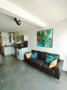 a living room with a black couch and a kitchen at Cap d'Agde Naturiste F in Cap d'Agde