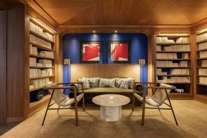 a library with a couch and two chairs and a table at Pavillon Faubourg Saint-Germain & Spa in Paris