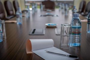 a table with a bottle of water and a pen and paper at Source of the Nile Hotel - Namanve in Kampala