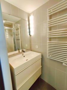 a white bathroom with a sink and a mirror at Cap d'Agde Naturiste F in Cap d'Agde