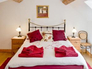 a bedroom with a bed with red pillows on it at Woodhouse Cottage in Hawarden