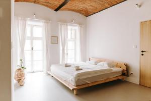 a bedroom with a bed with white walls and windows at Apartmány Starák v historickém centru Znojma in Znojmo