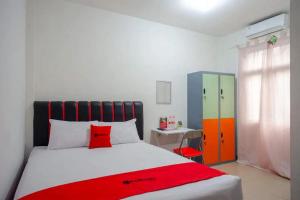 a bedroom with a bed with a red blanket on it at RedDoorz Syariah near Universitas Jenderal Soedirman 2 in Purwokerto