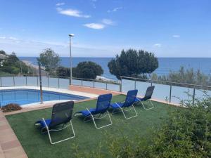 a group of chairs sitting next to a swimming pool at Villa Farell just in front of the sea in San Pol de Mar