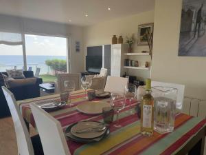 a dining room table with glasses and a bottle of wine at Villa Farell just in front of the sea in San Pol de Mar