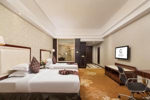 a hotel room with two beds and a desk at Maoming Country Garden Phoenix Hotel in Dianbai