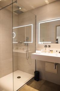 a bathroom with a shower and a sink and a mirror at H&ocirc;tel 1770 & Spa in Le Pontet